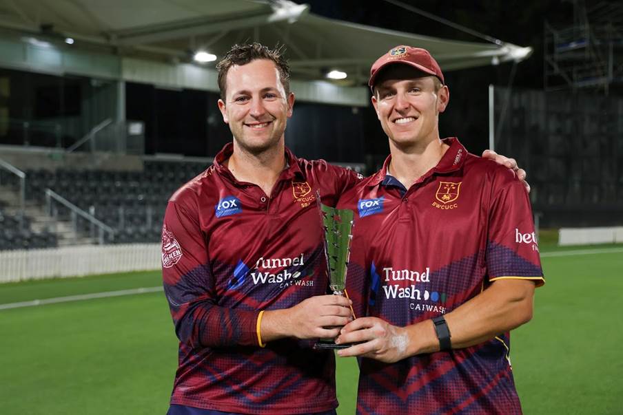 Two men in sports uniforms holding a trophy
Description automatically generated